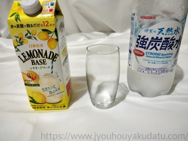 飲み干した後の空のグラスと日東紅茶 レモネードベースのパッケージ