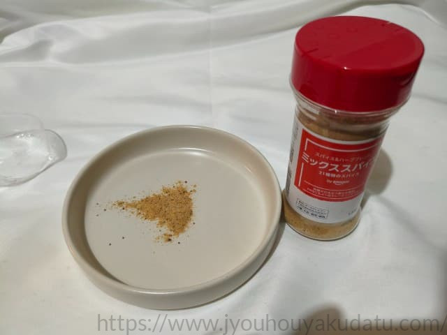 by Amazon ミックススパイスの中身を白い皿に出した様子。ハーブの緑、ペッパーの黒、塩などの粒が混ざっている。