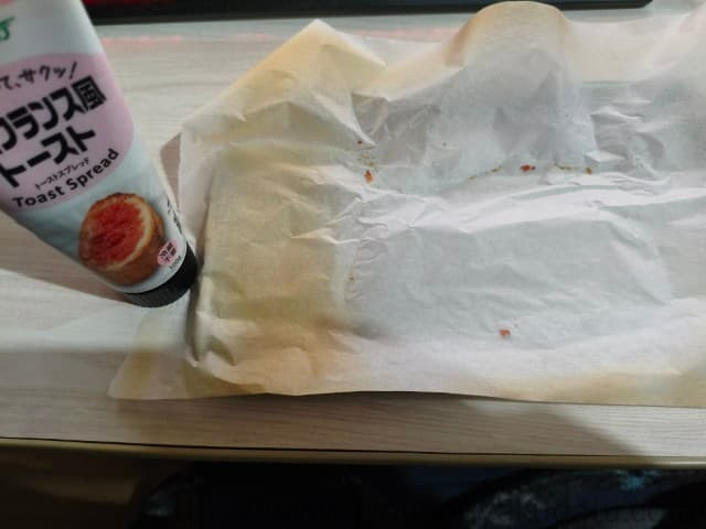 食べ終わった後の空になったトースター用のオーブントレーとその上のクッキングシート。パンくずが少し落ちているだけで、ほとんど汚れていない。