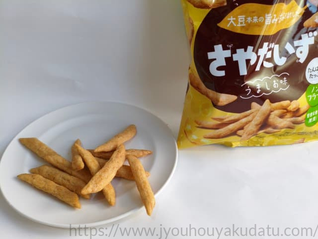 白い皿に盛られたカルビー「さやだいず うましお味」のスナック。細長く、ノンフライ特有の乾いた質感。