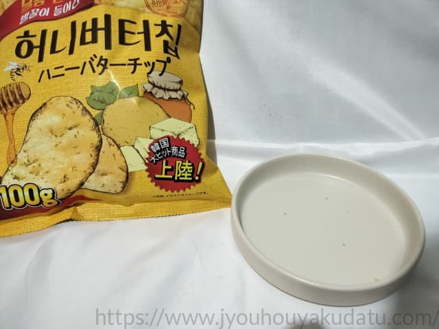 食べ終わった後の、何も乗っていない空の白い皿。わずかにチップスのくずが残っている。