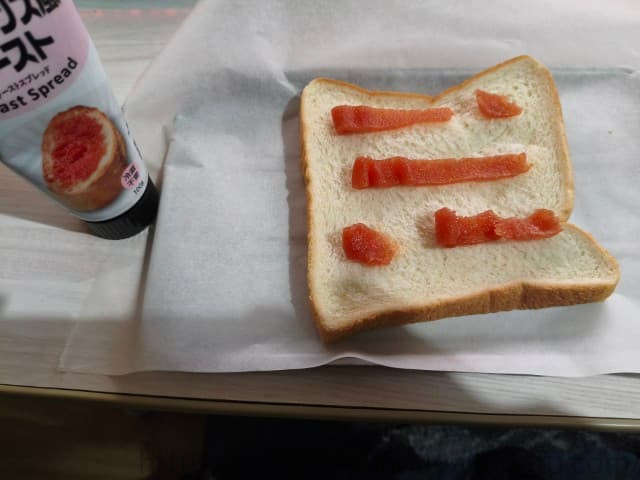 白い食パンにヴェルデの明太スプレッドをチューブから絞り出し、少し塗り広げた状態。明太子の濃いオレンジ色が見える。