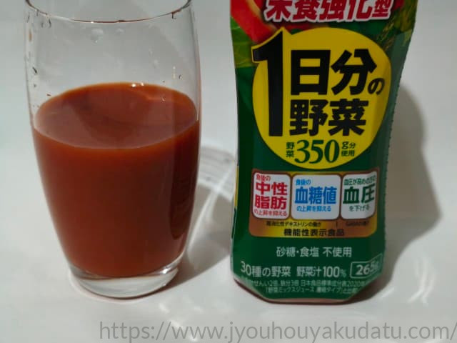 透明なグラスに注がれた「1日分の野菜 栄養強化型」。濃厚でとろみのあるオレンジがかった赤色のジュース。
