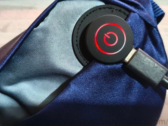 nerugooホットアイマスクの電源スイッチにUSBケーブルを繋いで充電中。ランプが赤く点灯している様子
