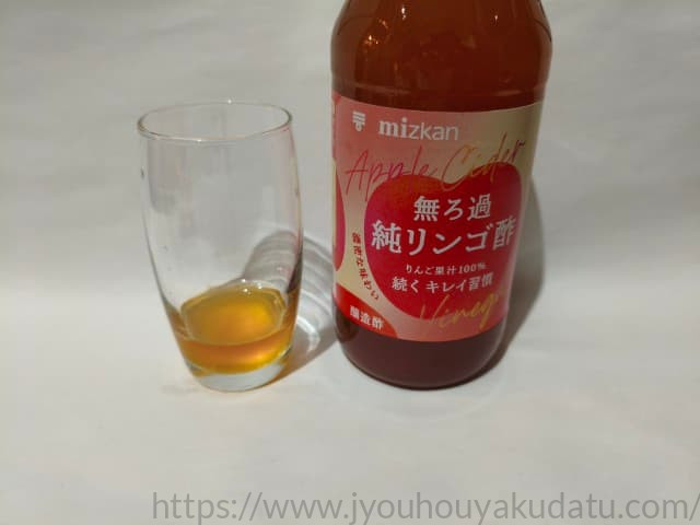 グラスに注がれた「ミツカン 無ろ過純リンゴ酢」の原液。無ろ過特有の濃い琥珀色。