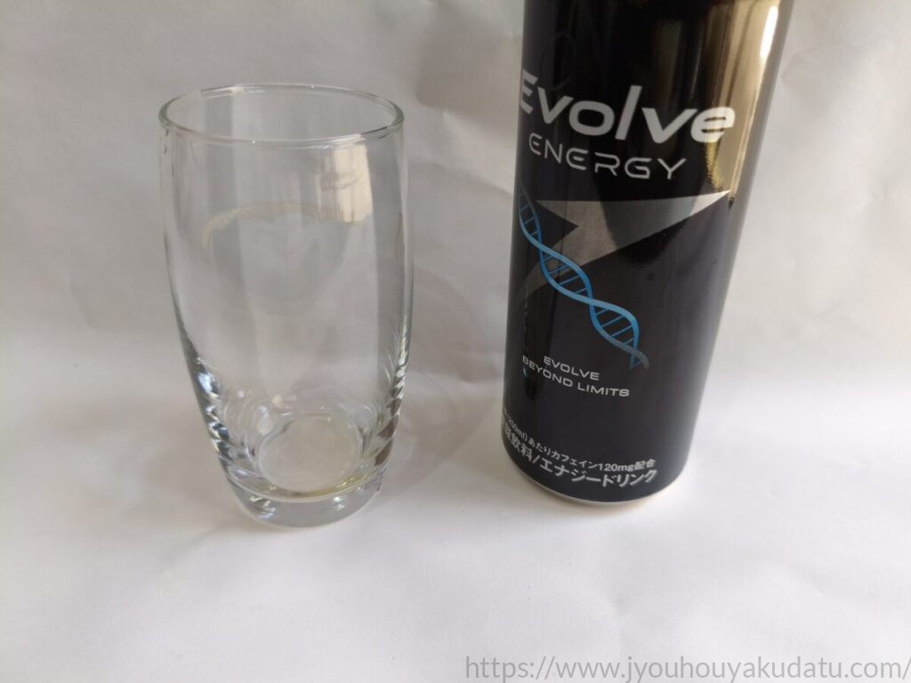飲み終わった後の空になった透明なグラス。奥には空のエナジードリンク「Evolve」の缶が立っており、美味しく飲みきった様子が伝わる。