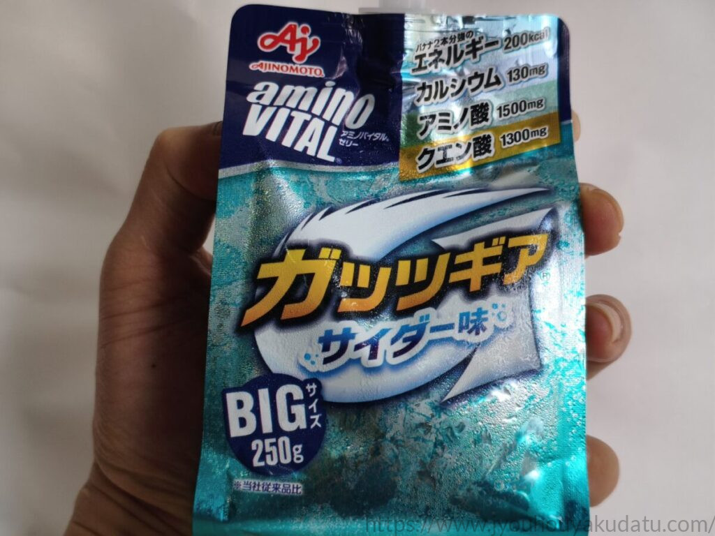 手に持たれたアミノバイタル ガッツギア サイダー味のパッケージ。250gの大容量サイズであることが視覚的にわかる。