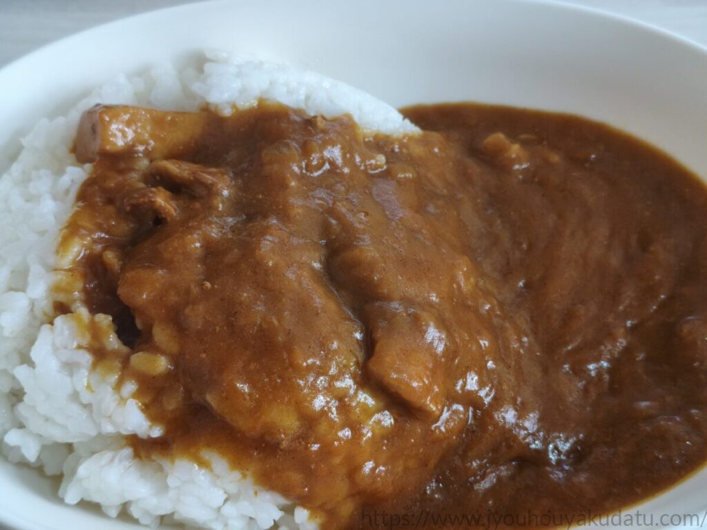 白い皿に盛り付けたMCC リオ ポークカレー。茶色いルーと豚肉の具材