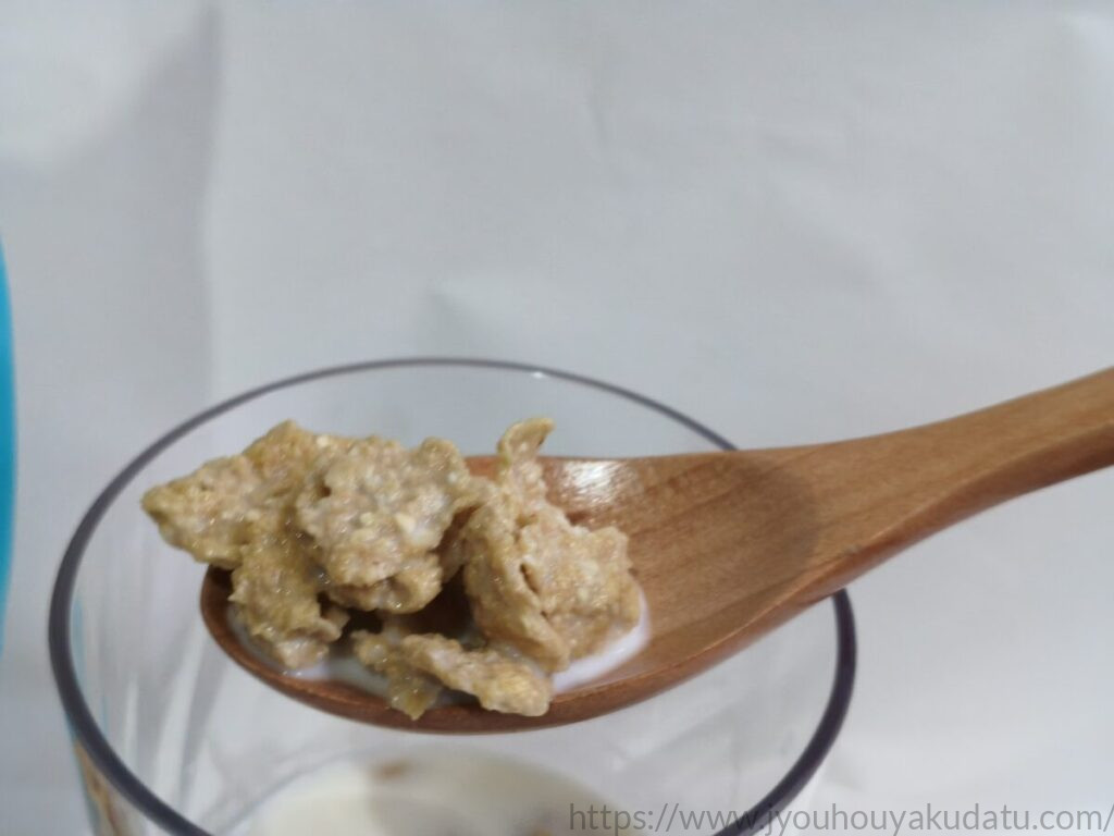 牛乳をかけたオートミールフレークを木製スプーンですくった様子