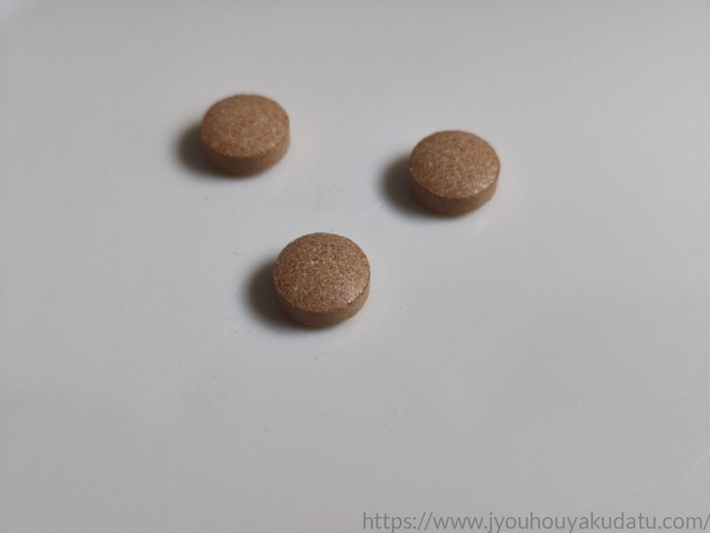 純・シナモンのめぐみの茶色く平たい円形タブレット3粒のアップ