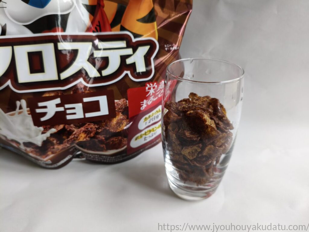 透明なグラスに入れた茶色いコーンフロスティ チョコと商品パッケージ