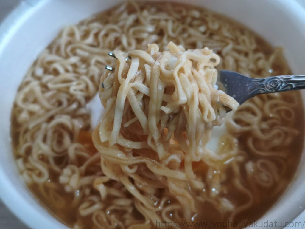 たまごをおとして食べる チキンラーメンどんぶりの調理後の麺をフォークですくい上げた様子