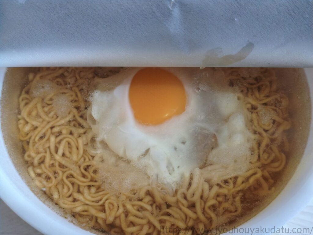 生卵を入れたチキンラーメンどんぶりに熱湯を注いだ直後の状態。黄身の周囲で白身が白くなり始めている